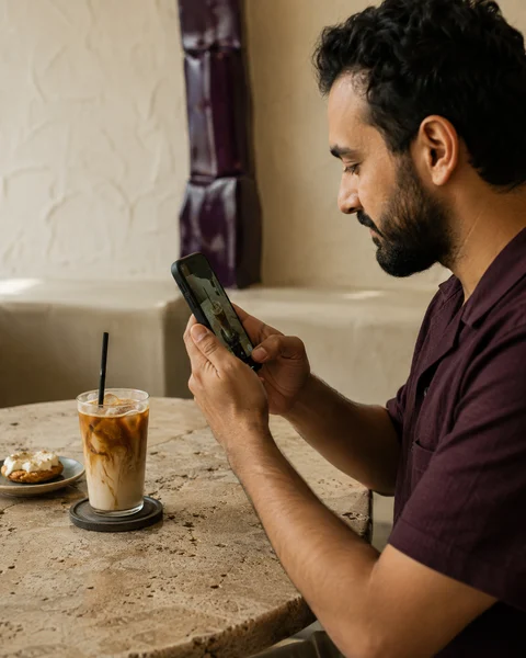 صورة توضيحية لصانع محتوى بيصوّر قهوة في مقهى محلّي.